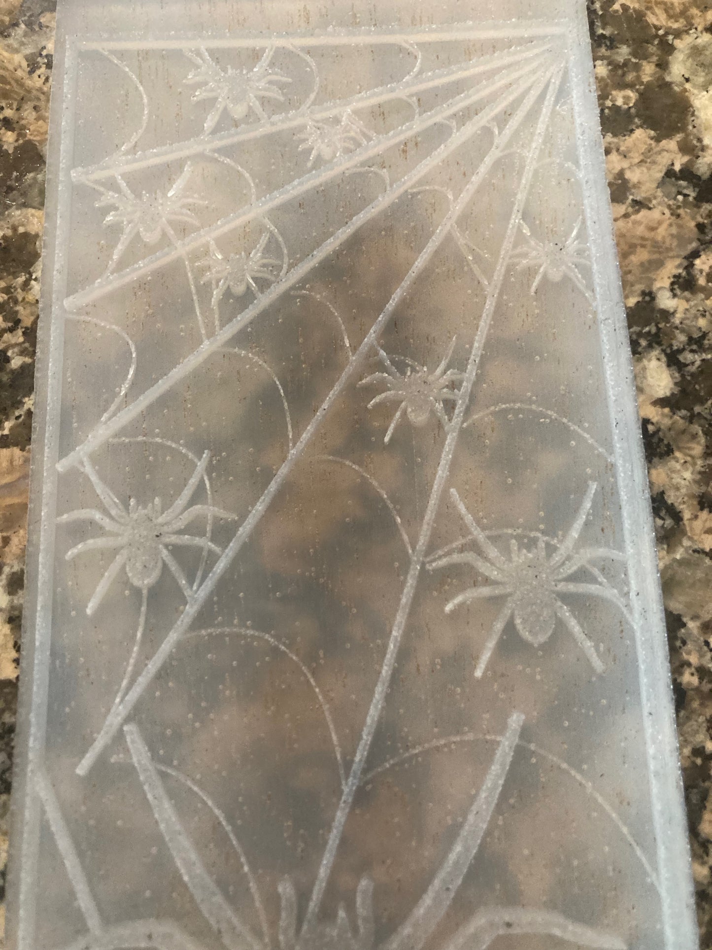 Clear silicone mat with spiderweb and spider design on a textured surface