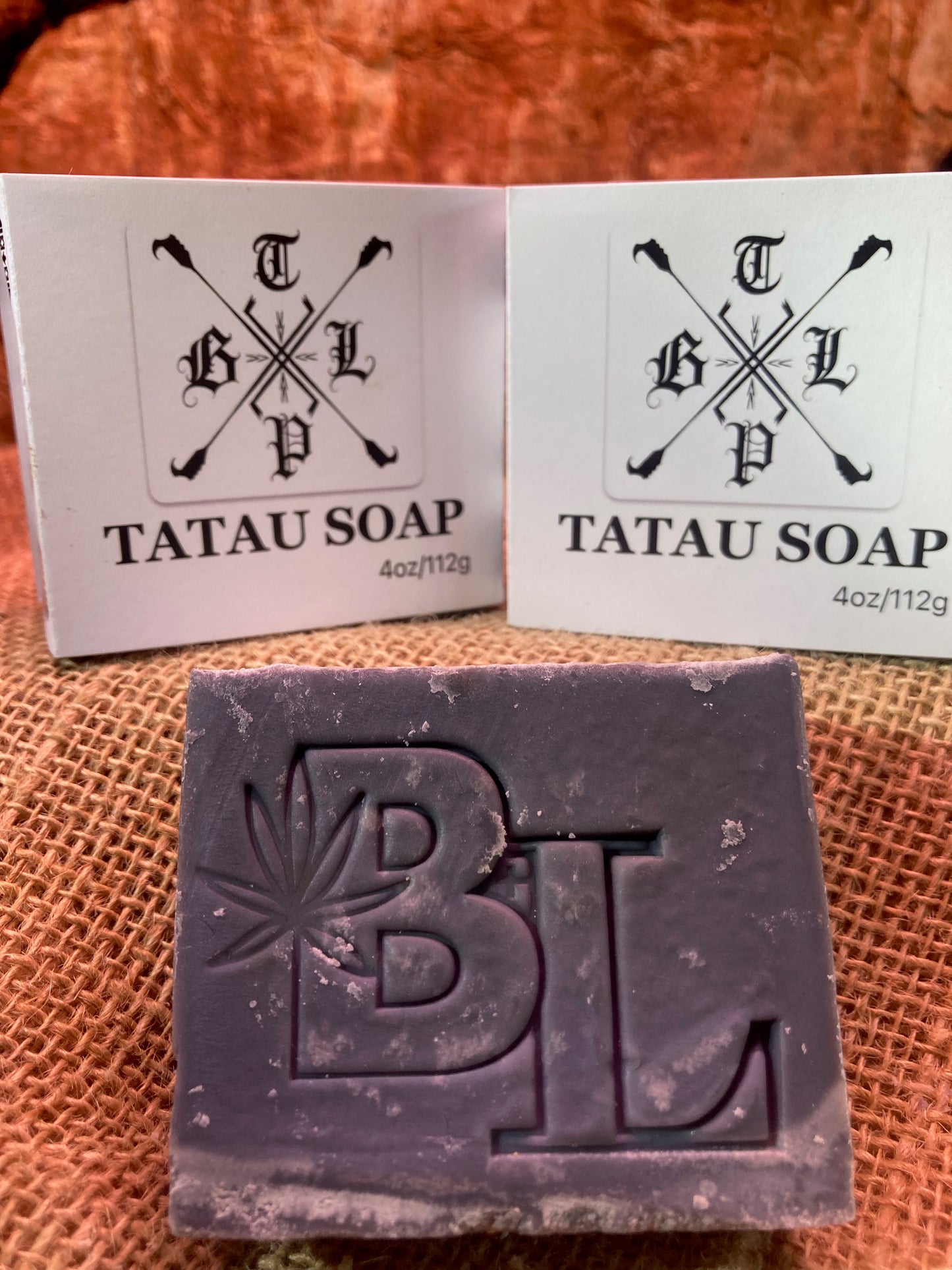 Bar of Tatau Soap with packaging on a textured surface
