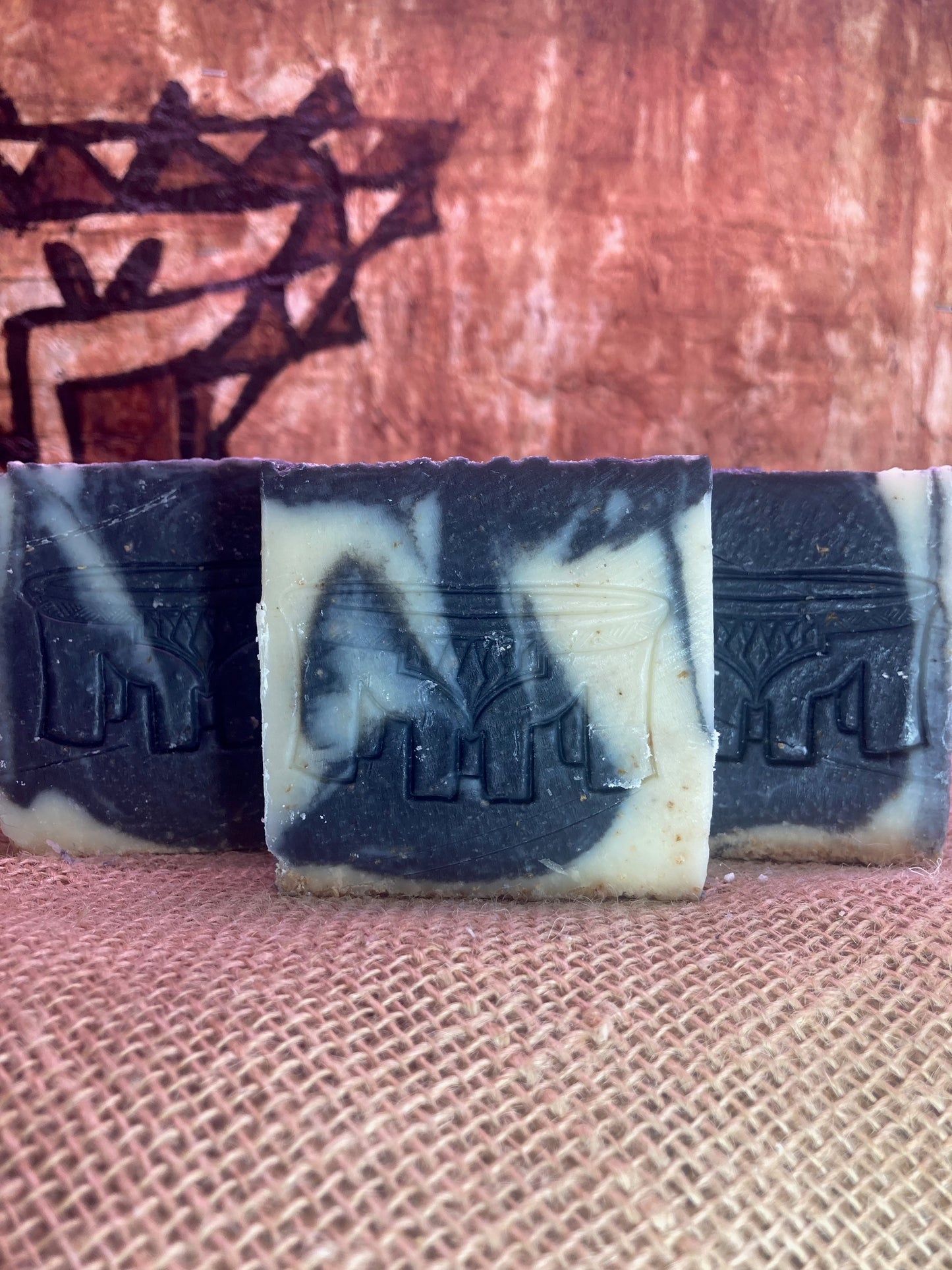 Three bars of soap with black and white marbled pattern on a textured surface