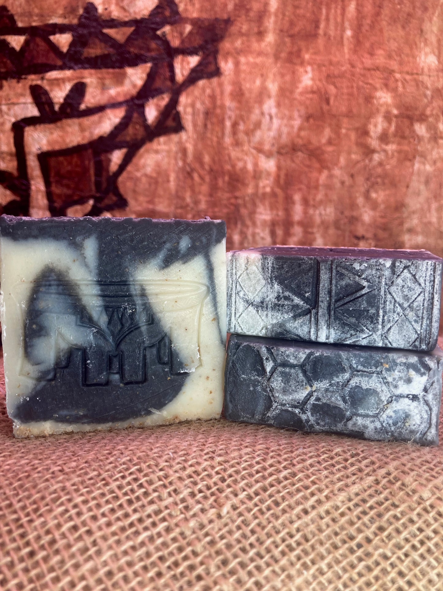 Three bars of soap with embossed designs on a textured surface