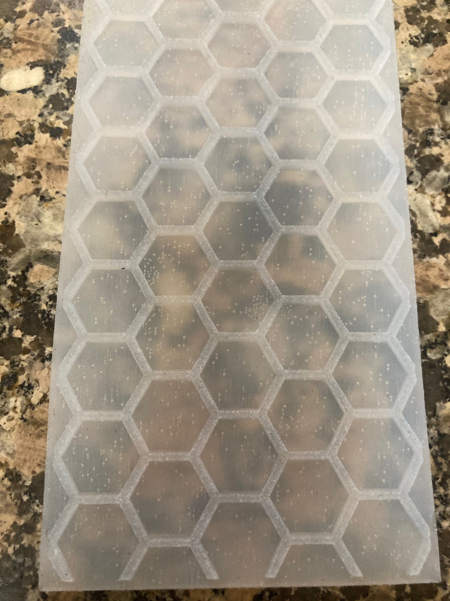 Clear silicone mold with hexagonal compartments on a granite countertop