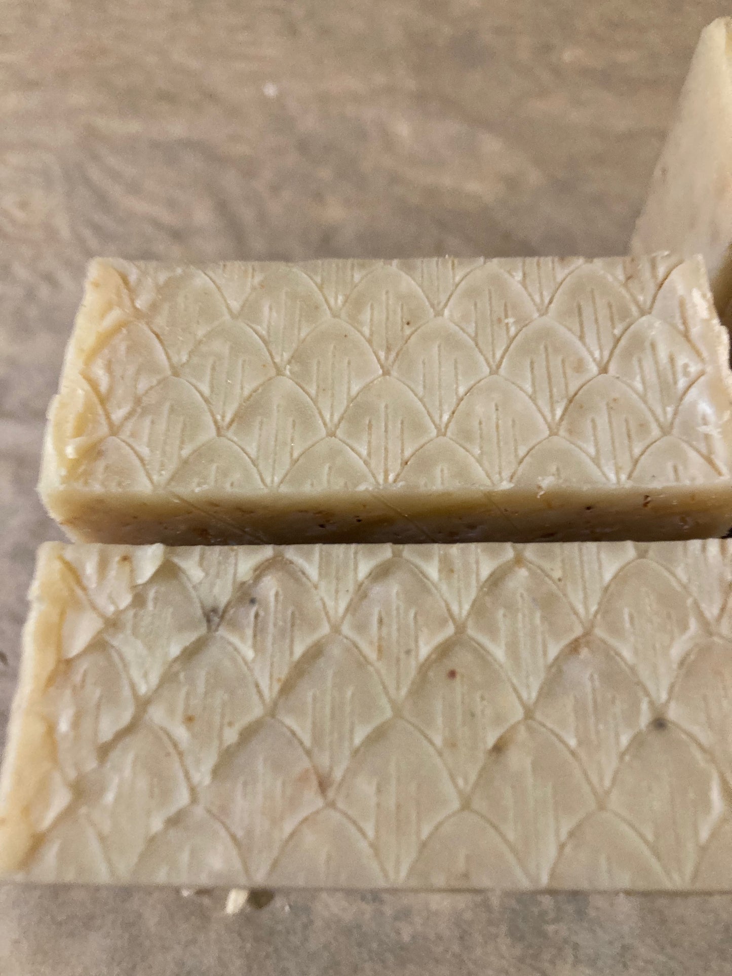 Two bars of soap with a textured pattern on a brown surface