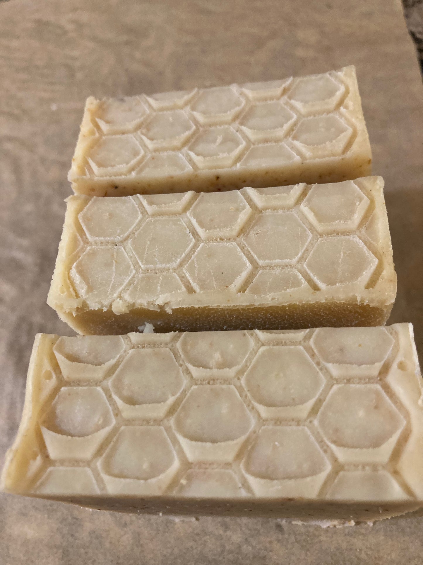 Three bars of soap with honeycomb pattern on a stone surface