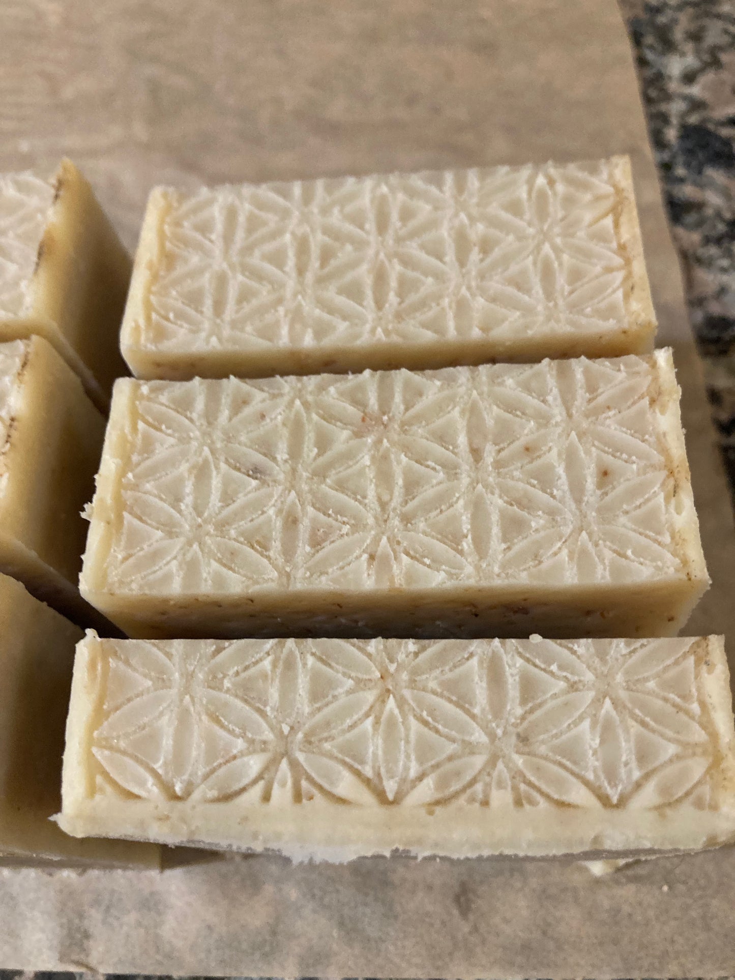 Three bars of soap with a geometric pattern on a brown surface