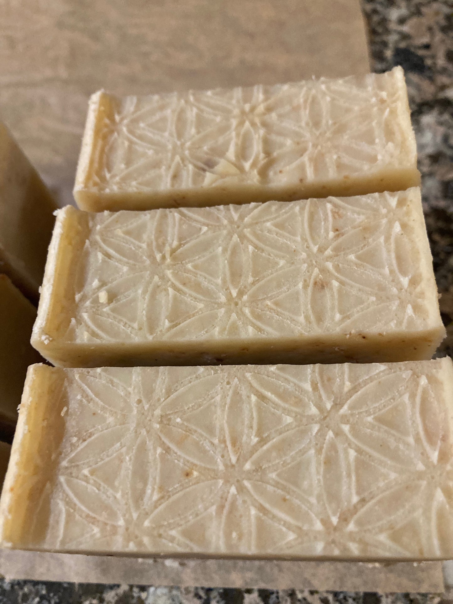 Three bars of soap with a geometric pattern on a brown surface