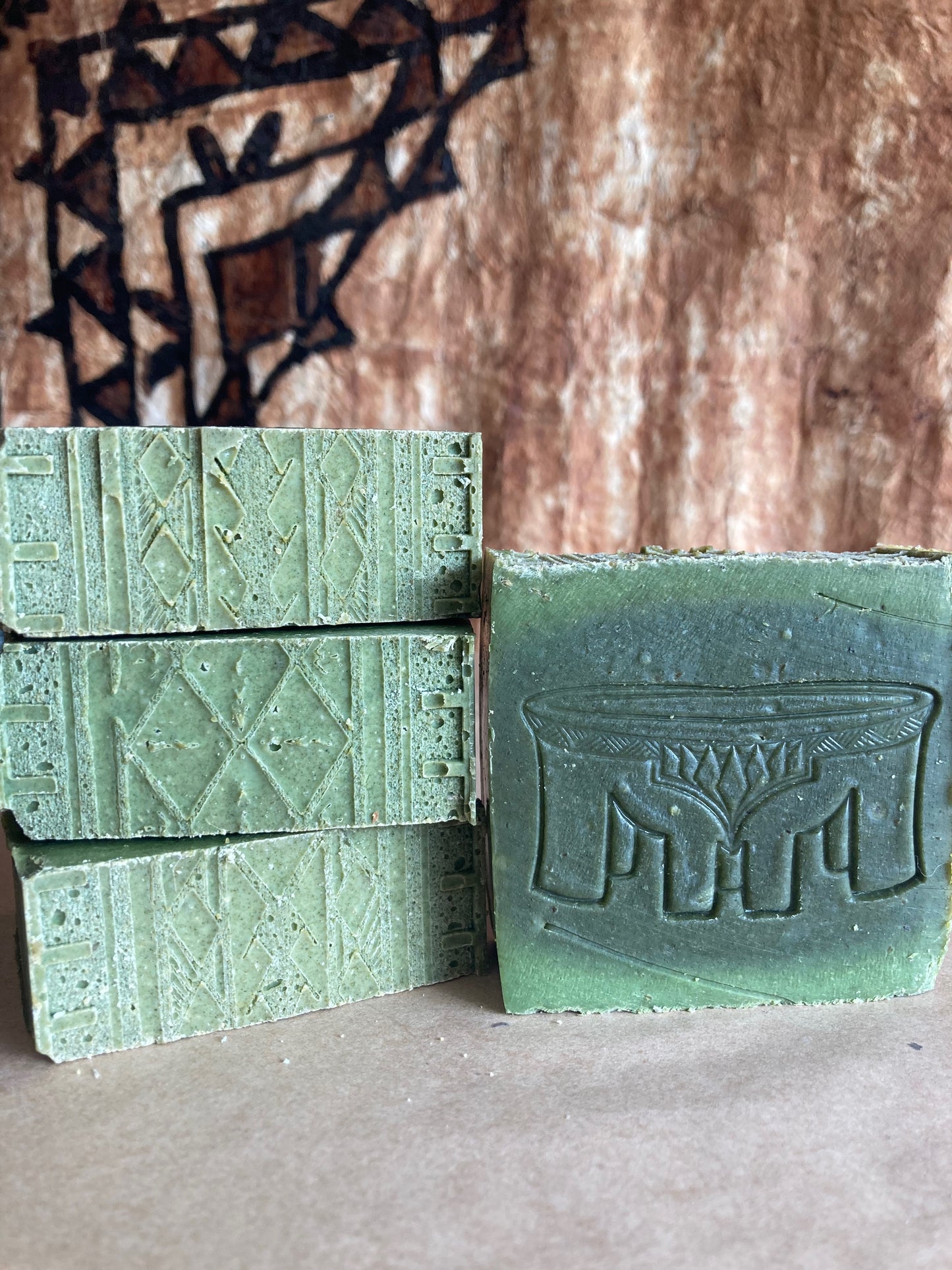 Four bars of green soap with textured surfaces on a Burlap Bag