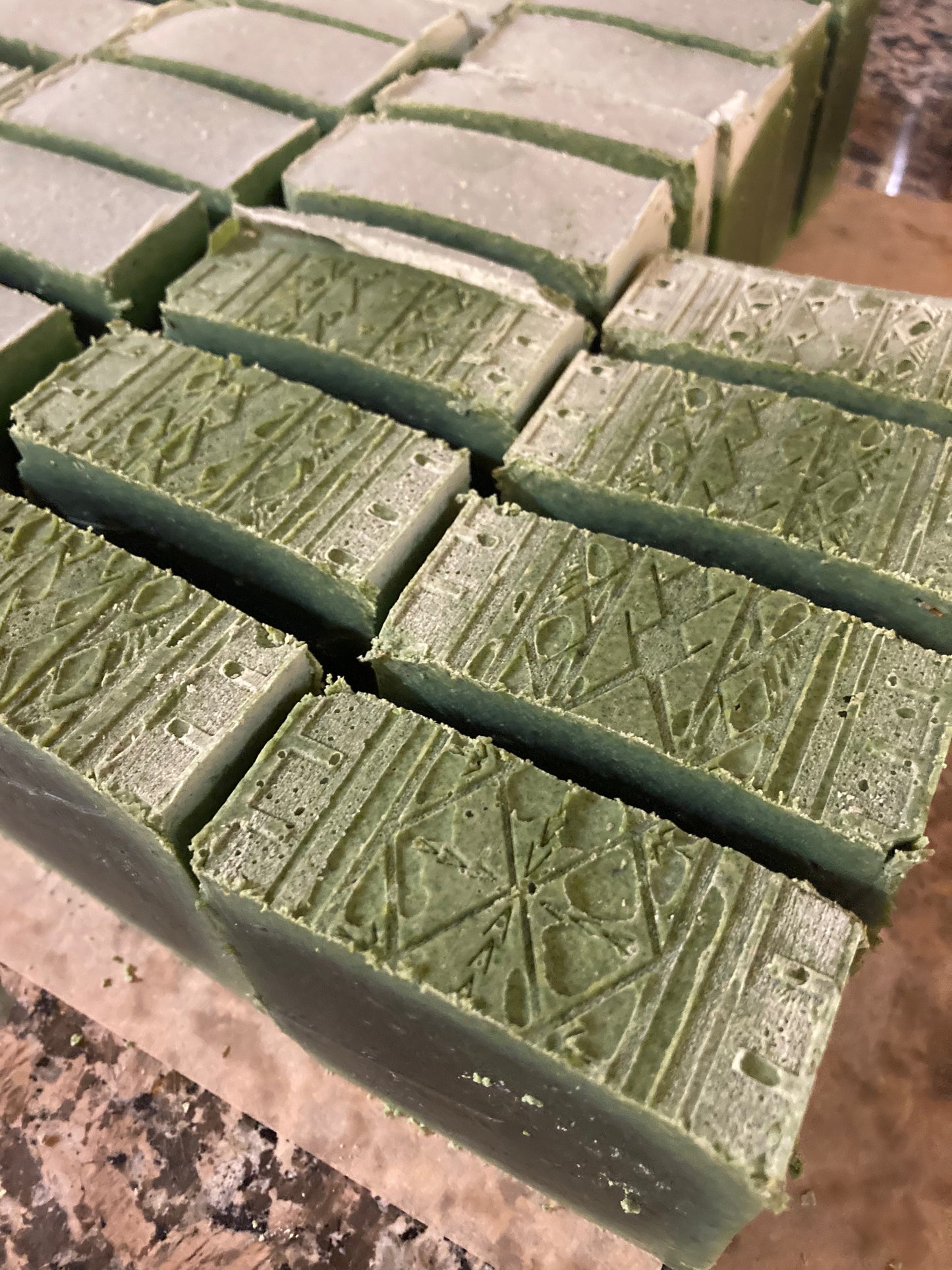 Green soap bars with a textured surface on a deli sheet and granite surface