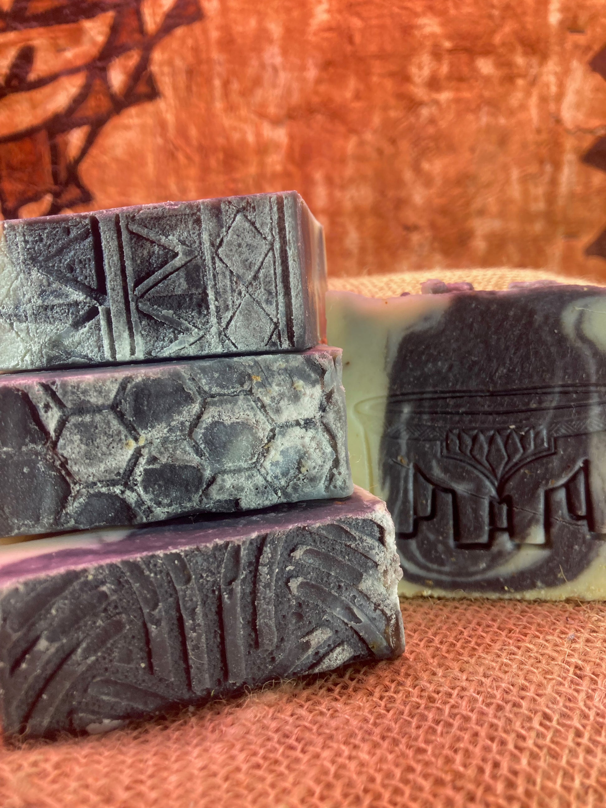Three bars of soap with textured surfaces on a textured orange background