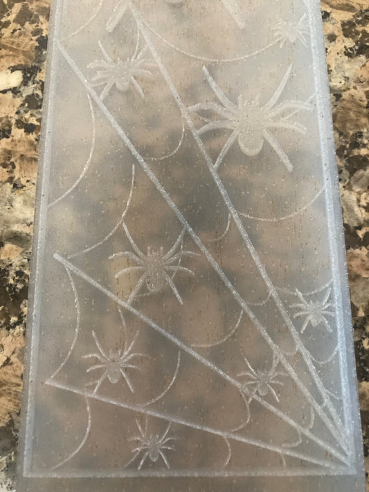 Transparent silicone mold with spiderweb and spider designs on a marble surface