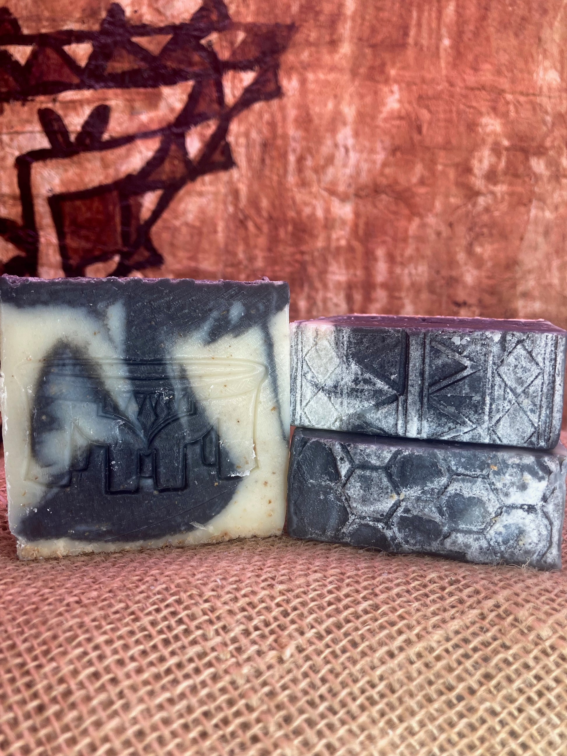 Three bars of soap with embossed designs on a textured surface