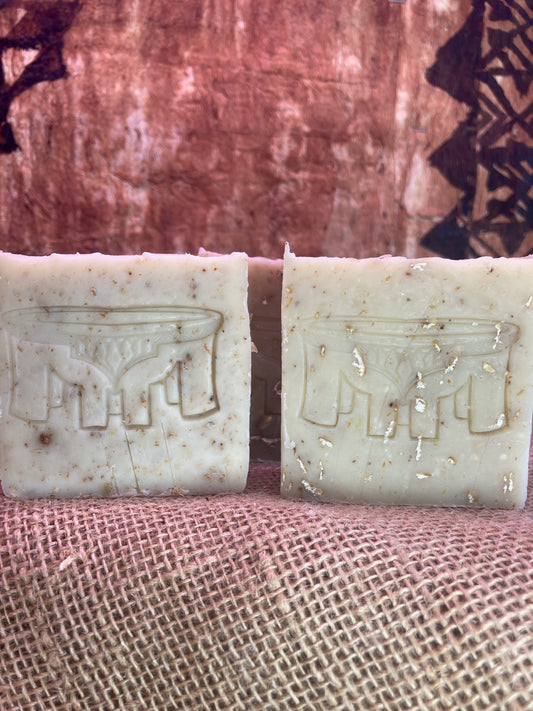Two soap bars with embossed designs on a textured fabric background
