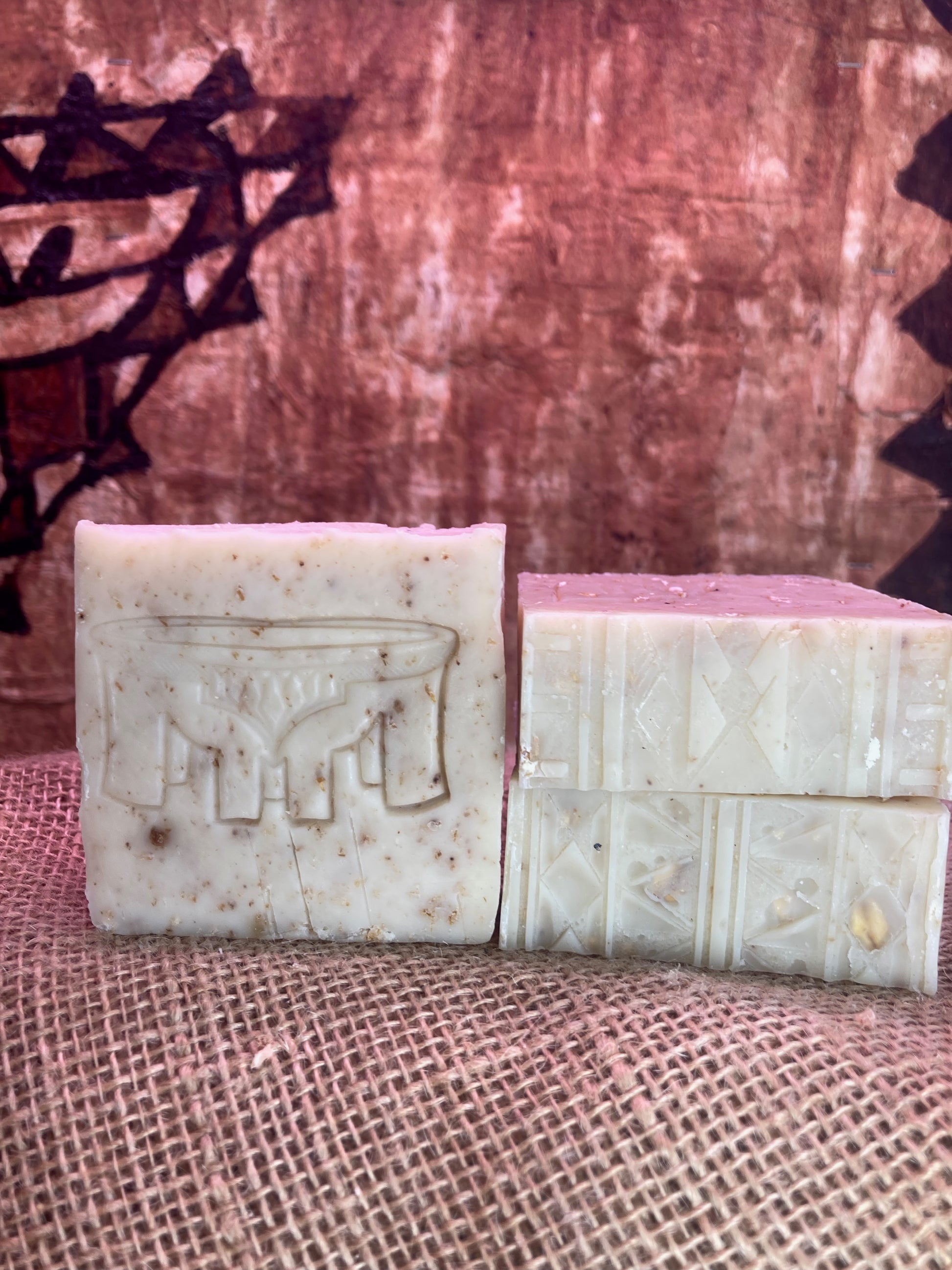 One Soap with Kava Bowl imprint next to Two soap bars with Tatau imprint designs on a textured surface