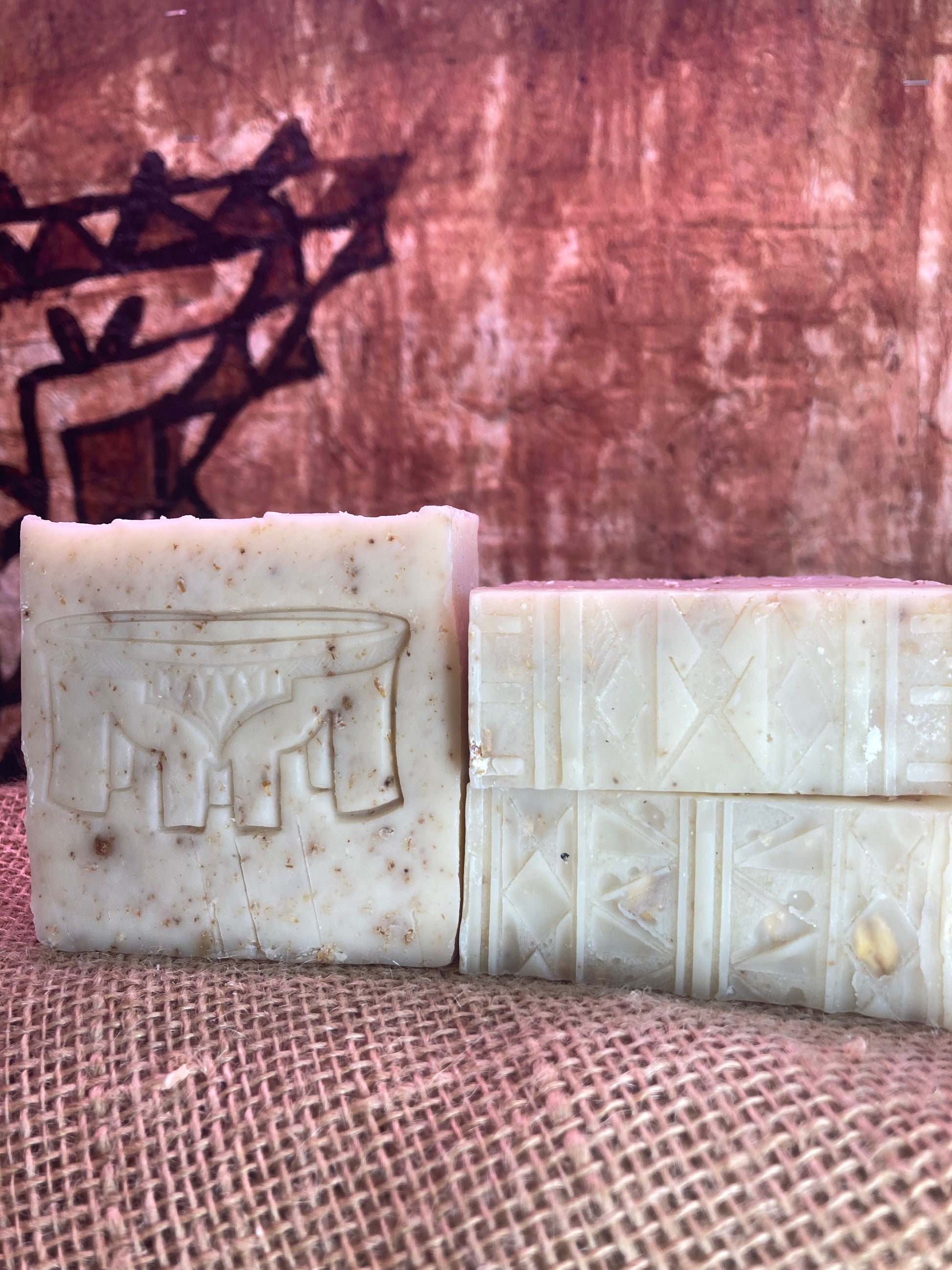 One Soap with Kava Bowl imprint next to Two soap bars with Tatau imprint designs on a textured surface