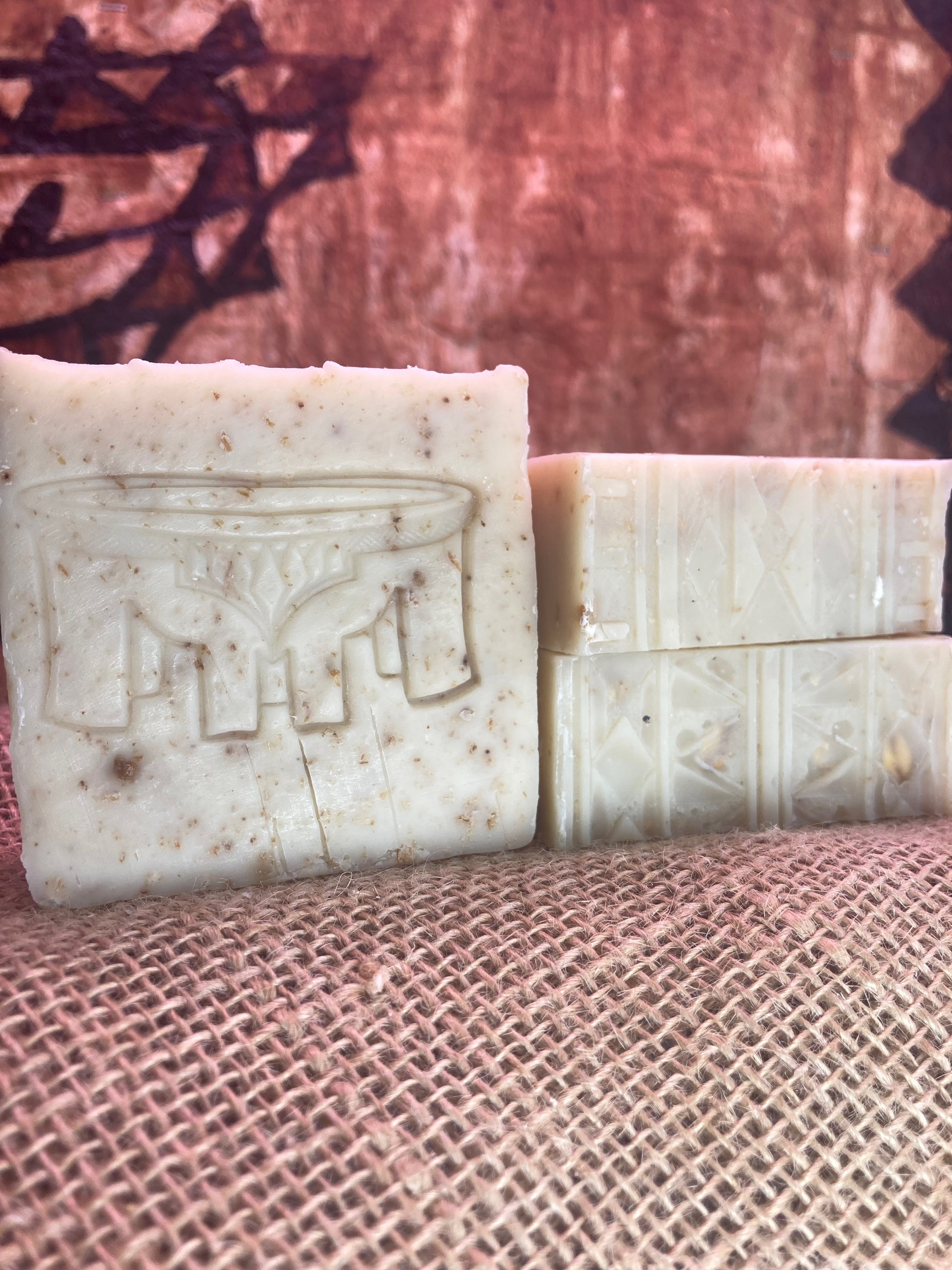 One Soap with Kava Bowl imprint next to Two soap bars with Tatau imprint designs on a textured surface