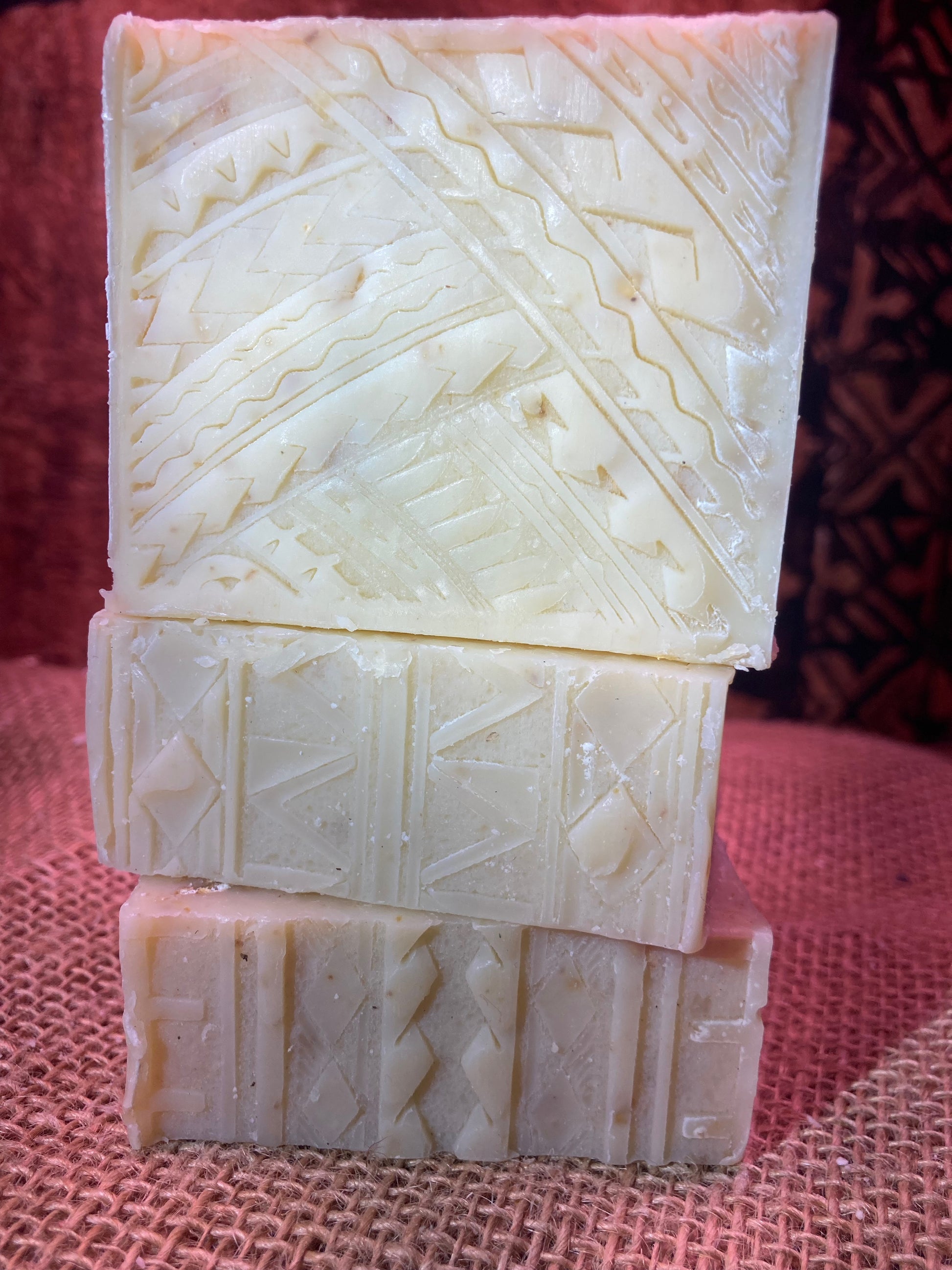 Three bars of soap with a textured pattern stacked on a textured surface