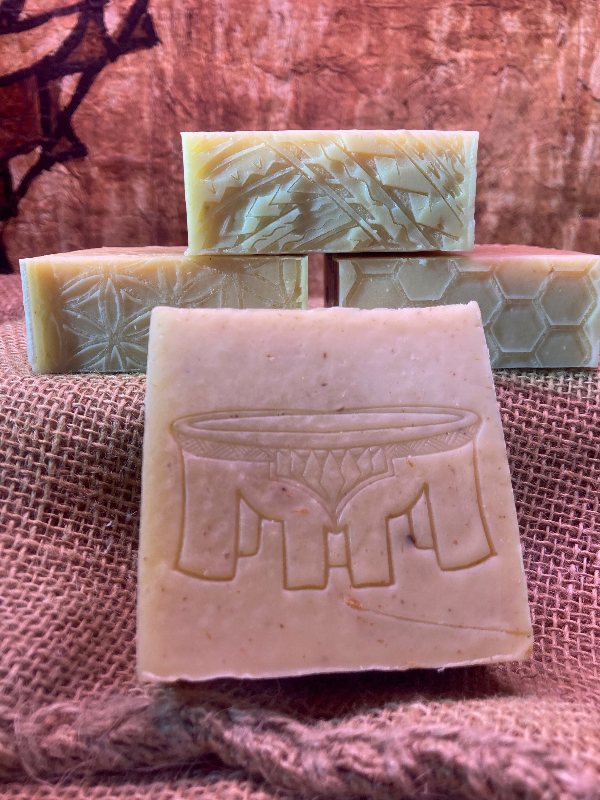 Stack of handmade soap bars with embossed designs on a textured fabric background
