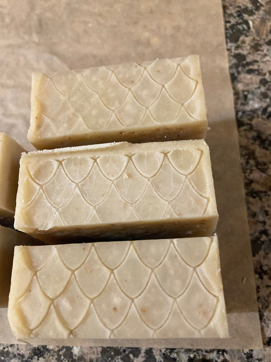 Three bars of soap with a textured pattern on a brown surface